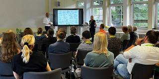 Nadine Roßa erklärt den Teilnehmenden ihre graphische Darstellung der Tagungsergebnisse. Daneben der Moderator Jan-Martin Wiarda.