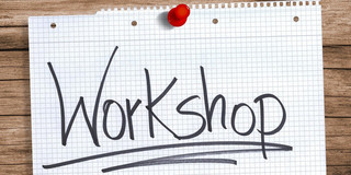 A white sheet of paper with Workshop handwritten on it hangs on a pinboard.