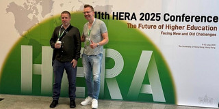 Peter Woelert (links) und Uwe Wilkesmann (rechts) vor dem Plakat der HERA Conference.